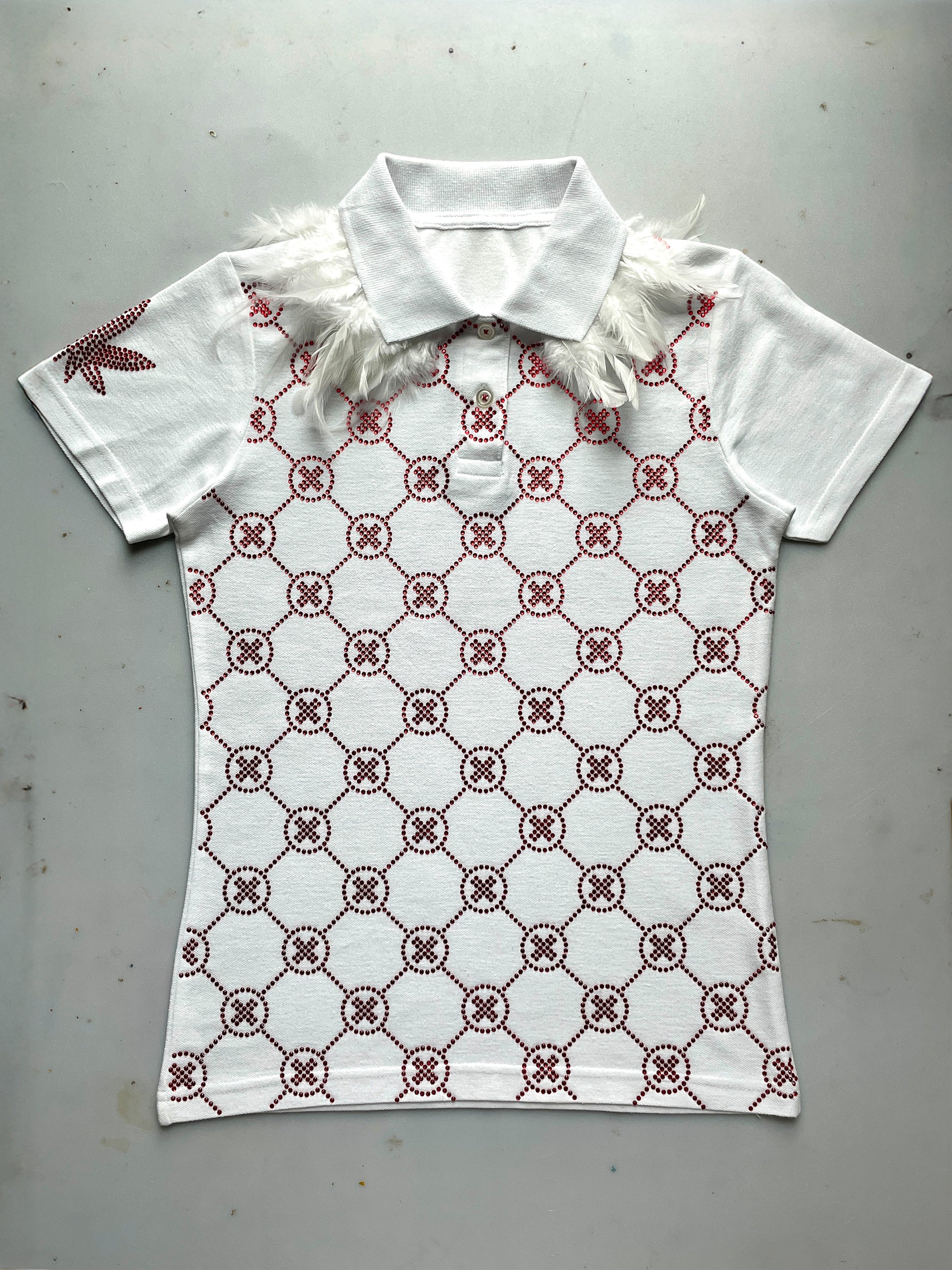 Witte polo met rode crystal gems, all-over monogram patroon en veren details op de schouders.